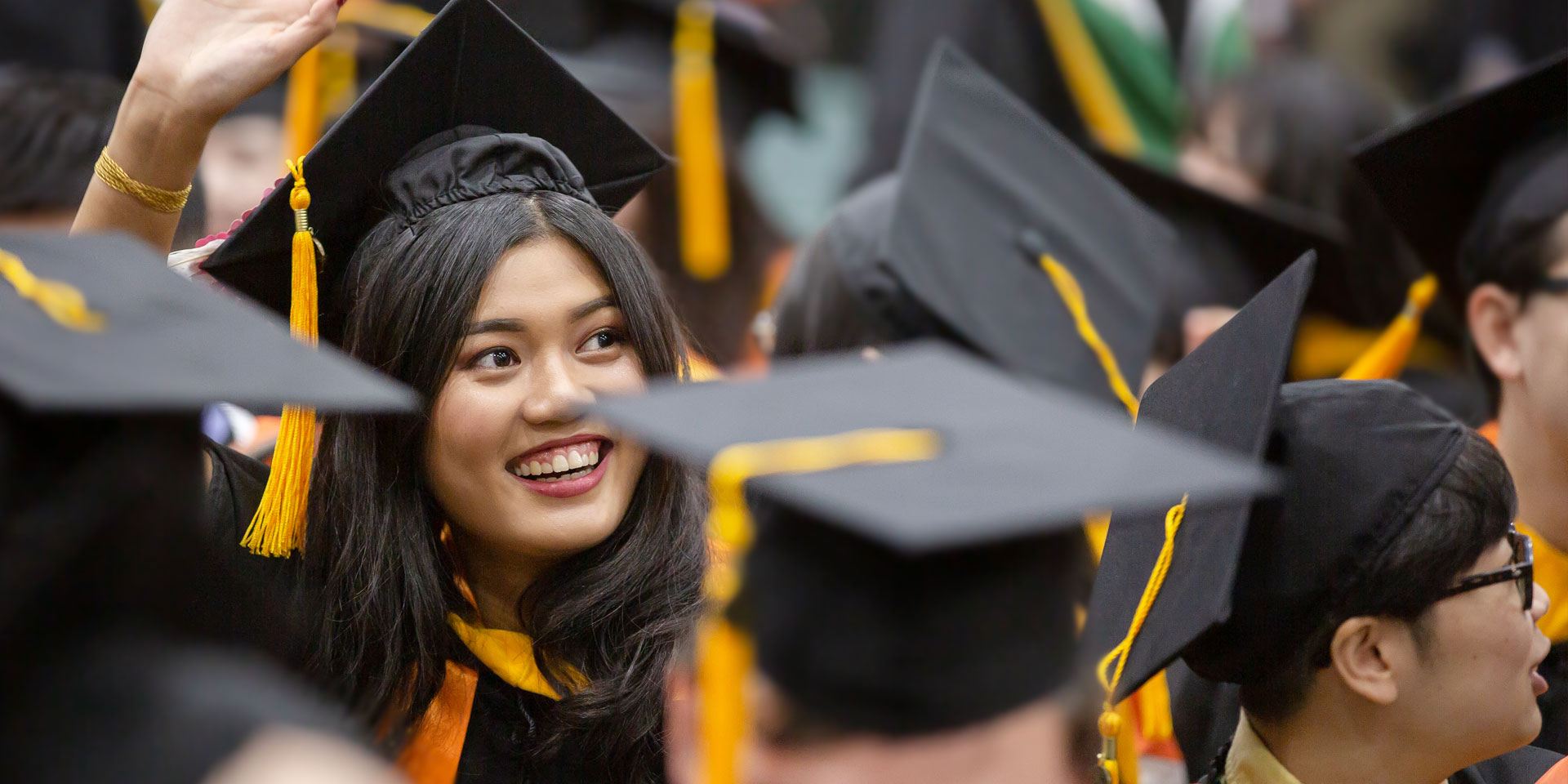 Master of Science in accounting student Meichen Lin waves to friends in the crowd during one of three fall commencement ceremonies for the Naveen Jindal School of Management.